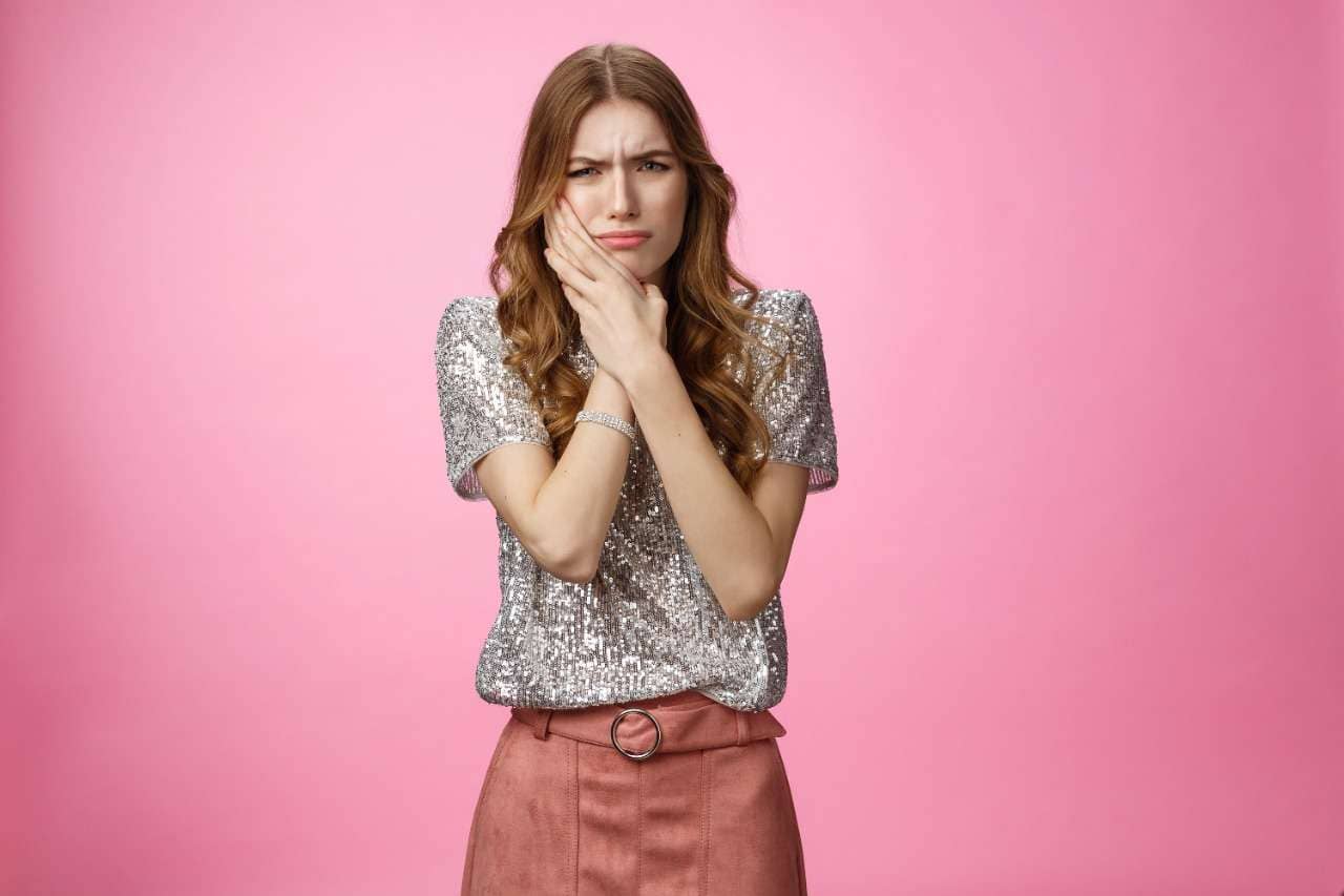 Close up of happy young woman with fresh glowing skin tone, showing beautiful white smile and grinning carefree, happy about valentines day, standing on pink background teeth whitening boca raton