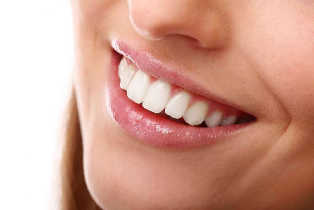 Cerca de una joven feliz con un tono de piel brillante y fresco, mostrando una hermosa sonrisa blanca y sonriendo despreocupada, feliz por el día de San Valentín, de pie sobre un fondo rosa blanqueamiento dental boca raton